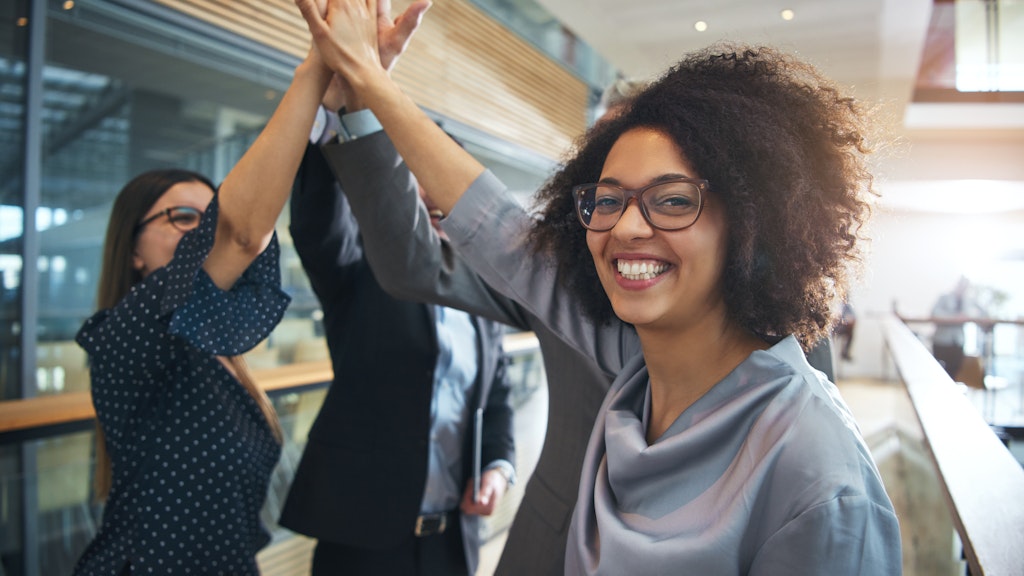 A group of at least three adults giving a collective high-five gesture. A Black female participant is smiling and facing the camera.
