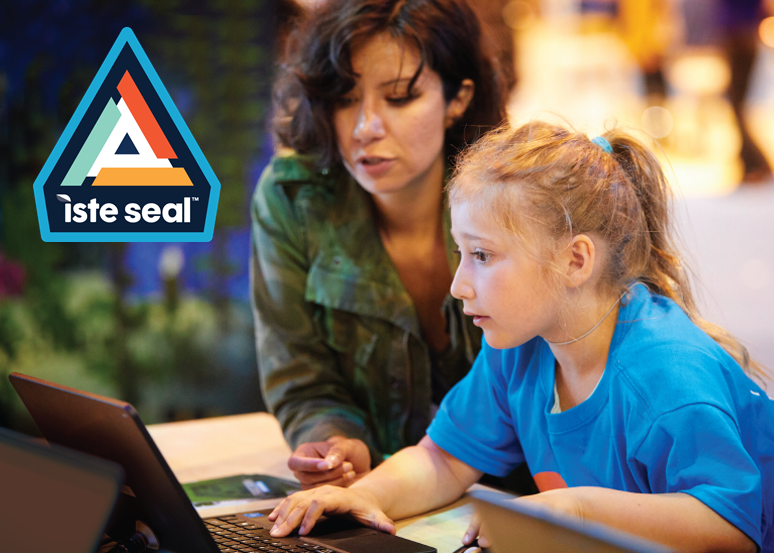 A woman with dark hair and a green shirt sitting next to a girl with blonde hair and a blue shirt looking at a laptop. A triangle shape image composed of blue, navy, light green, orange, and gold colors is layered over the image in the upper left corner, with the words ISTE Seal in white lowercase letters in the bottom of the triangle.